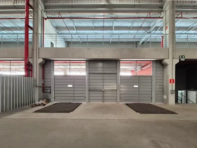 Vista interna do galpão com portões seccionados e plataformas niveladoras.